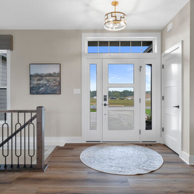 Parade of Homes model, The Lexi, front foyer with large rug and open glass front door