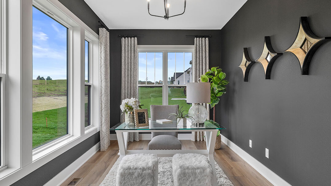 Parade of Homes model, The Lexi, flex room that is staged as an at home office. This room features dark walls with constrating white trim.